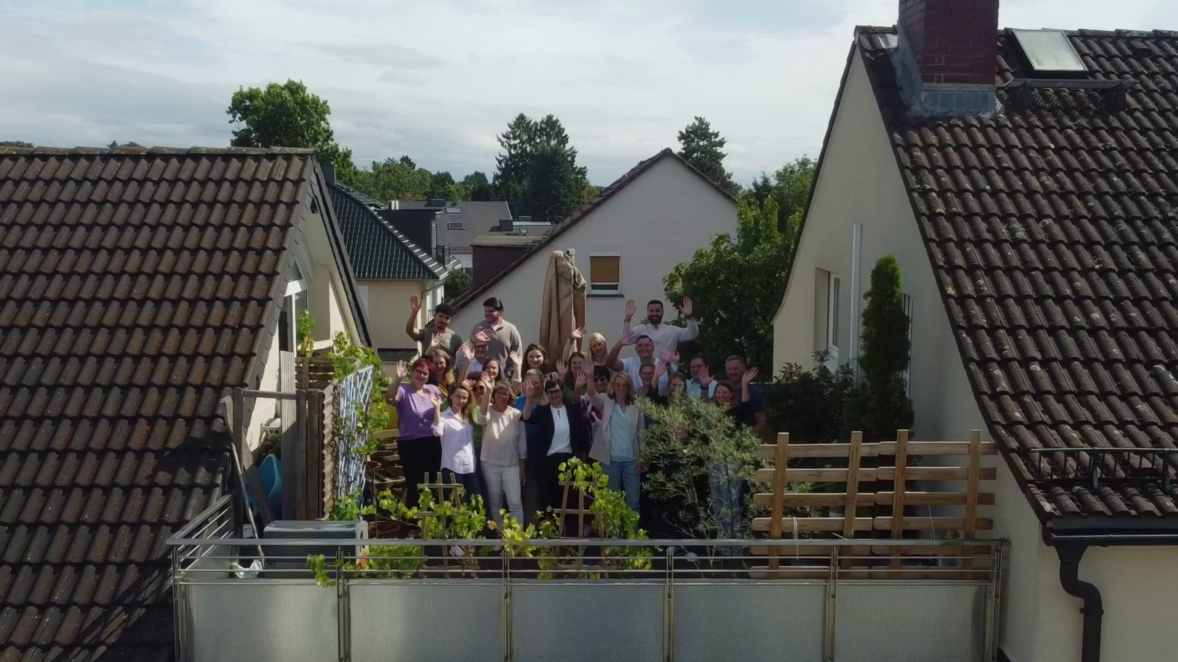 Kollegen winkend auf der Dachterrasse